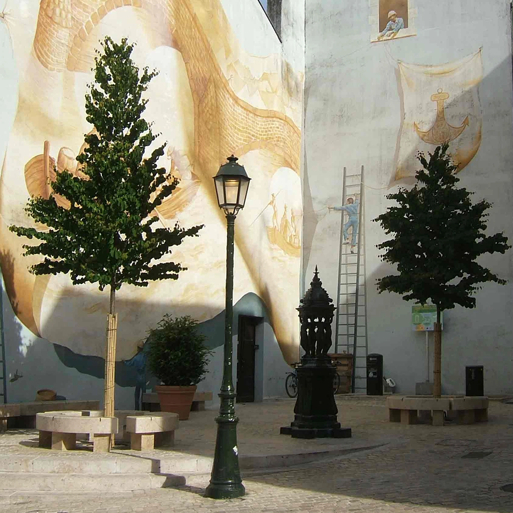 Zwei junge Alleebäume stehen vor einer modernen hellen Kirschenfassade