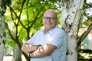 Mann lehnt an einer Birke