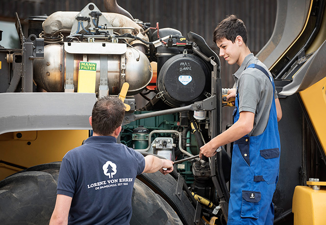 Ausbildung Landmaschinenmechatroniker bei Baumschule Lorenz von Ehren Ausbilder zeigt Azubi den Motor eines Radladers
