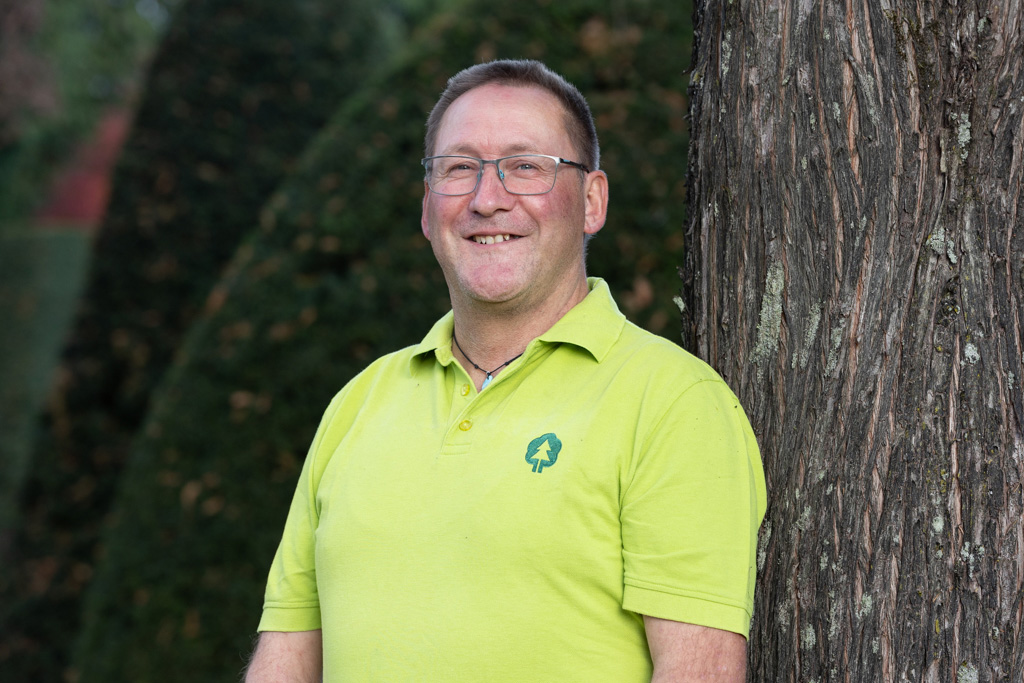 Mann lehnt an einem Baum